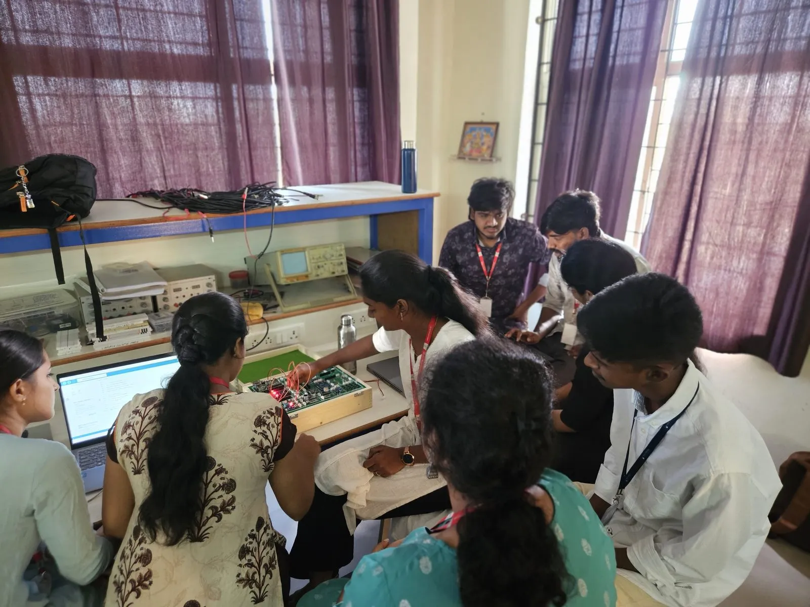 Students working together on an IoT trainer kit connected to a laptop