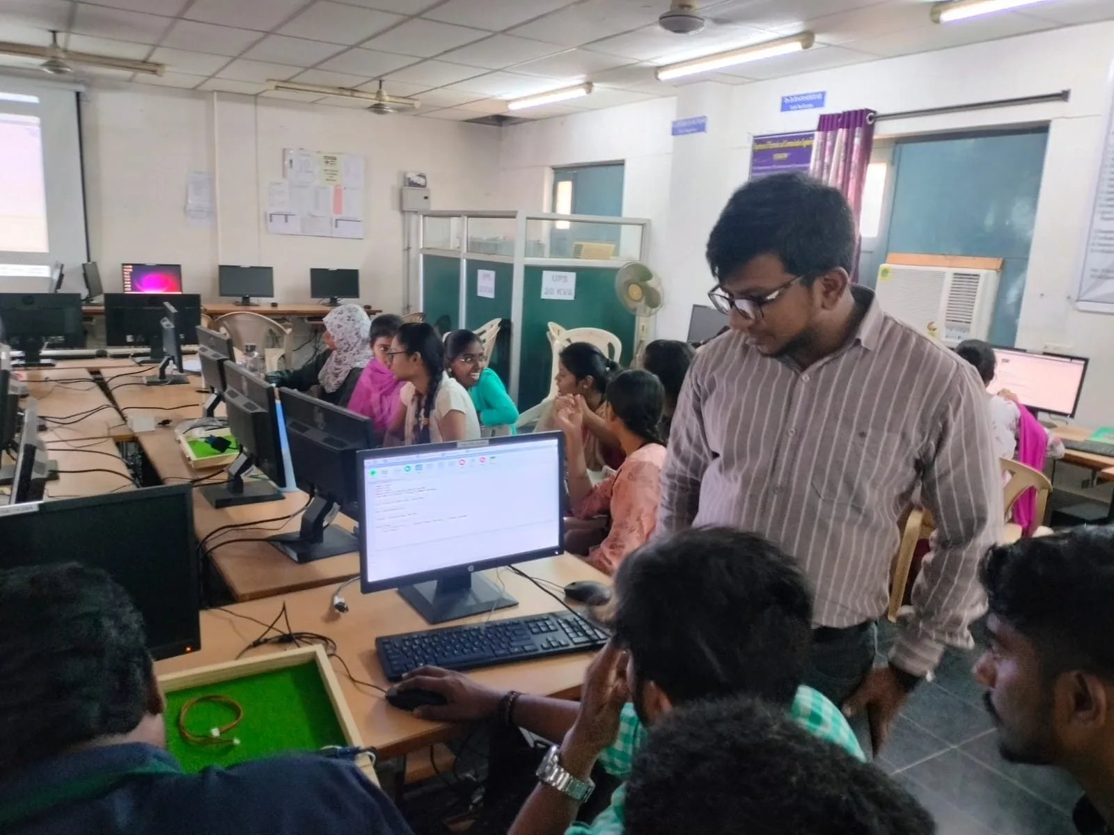 A trainer guiding students at a computer during a hands-on lab session