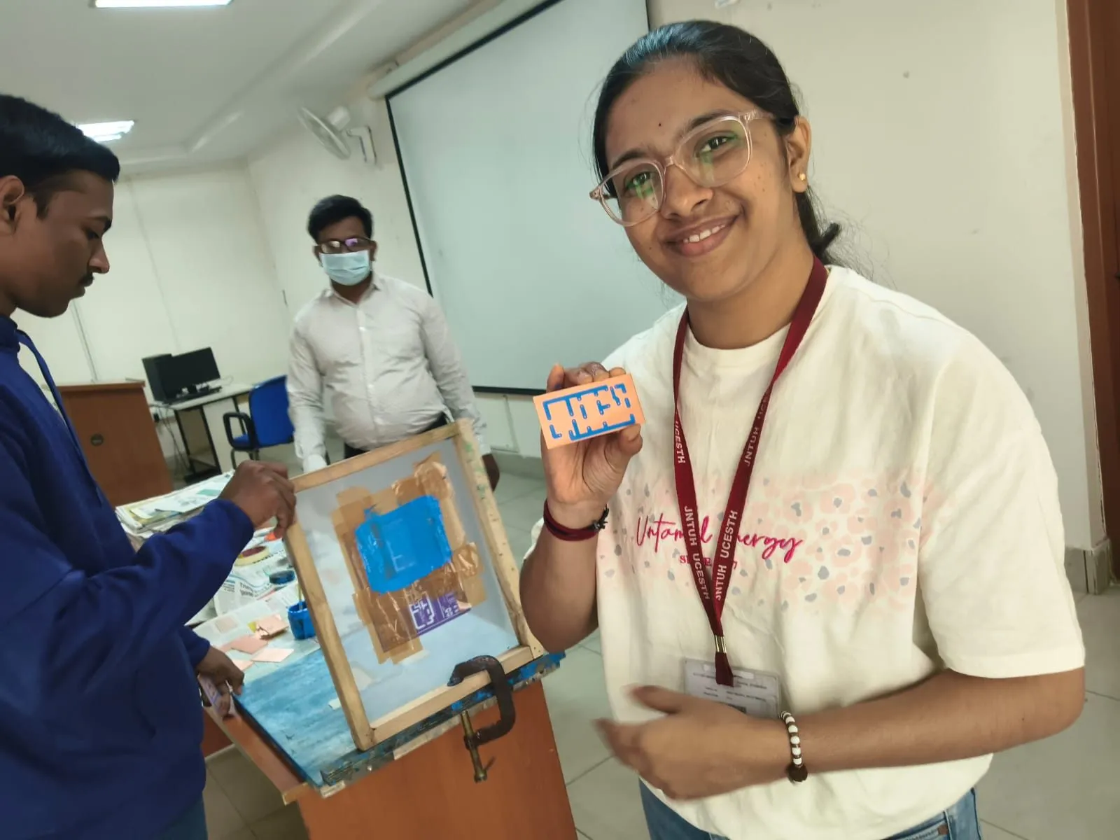 A student smiling while holding a PCB at the screen-printing stage