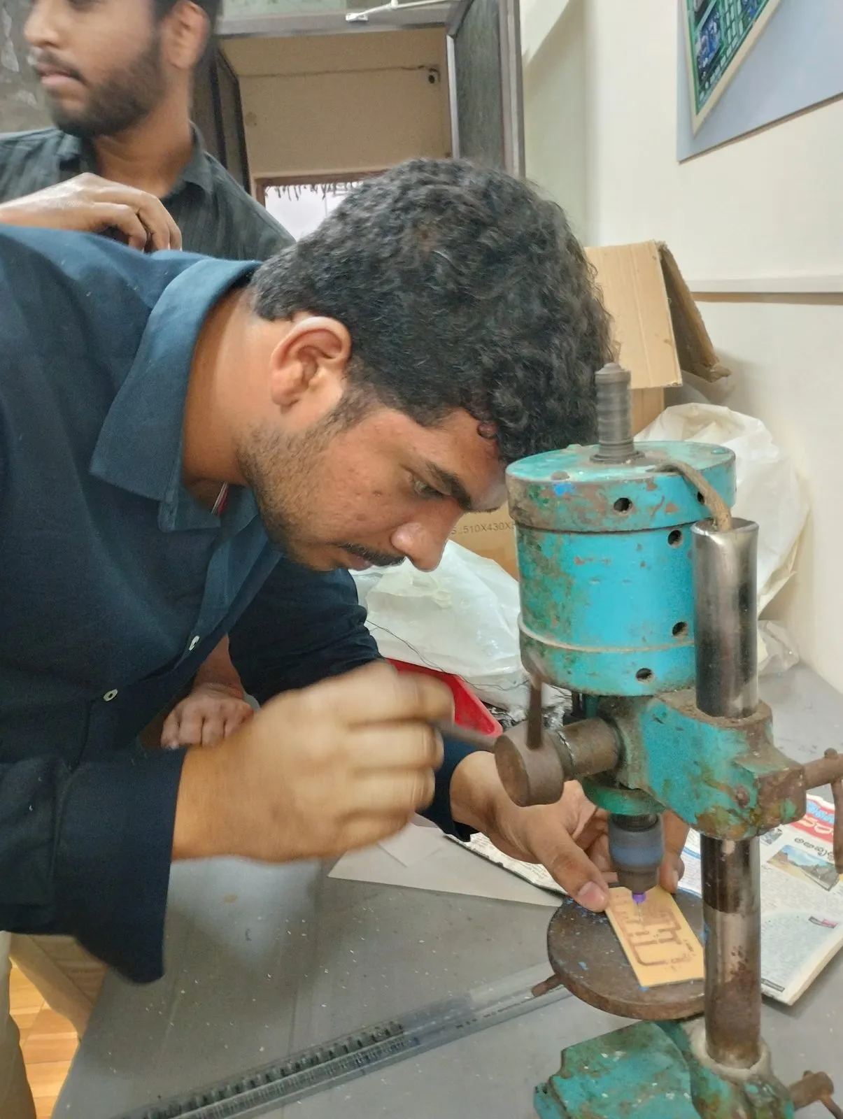 A participant drilling holes in a PCB