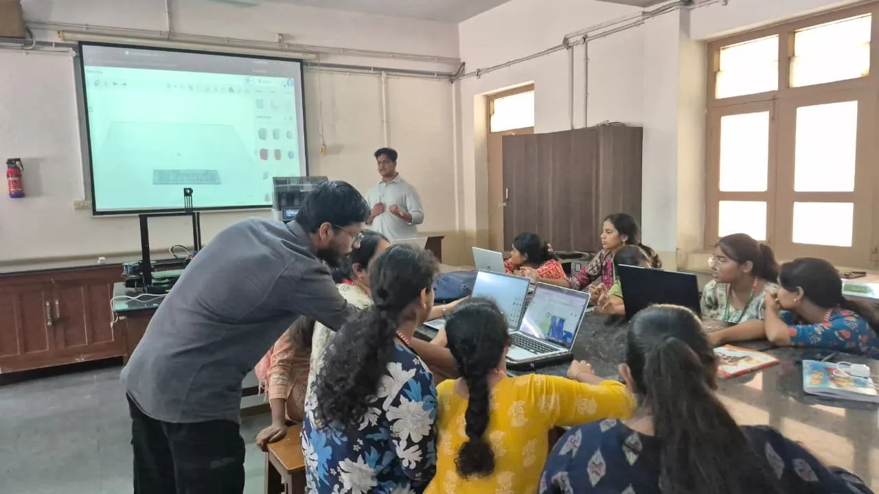 An instructor helping participants prepare models on laptops