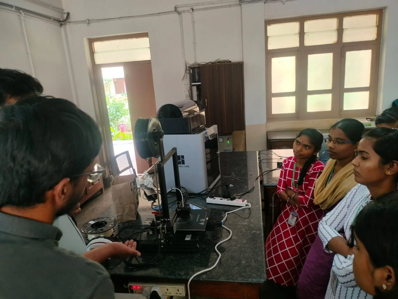 An instructor operating a 3D printer while participants watch