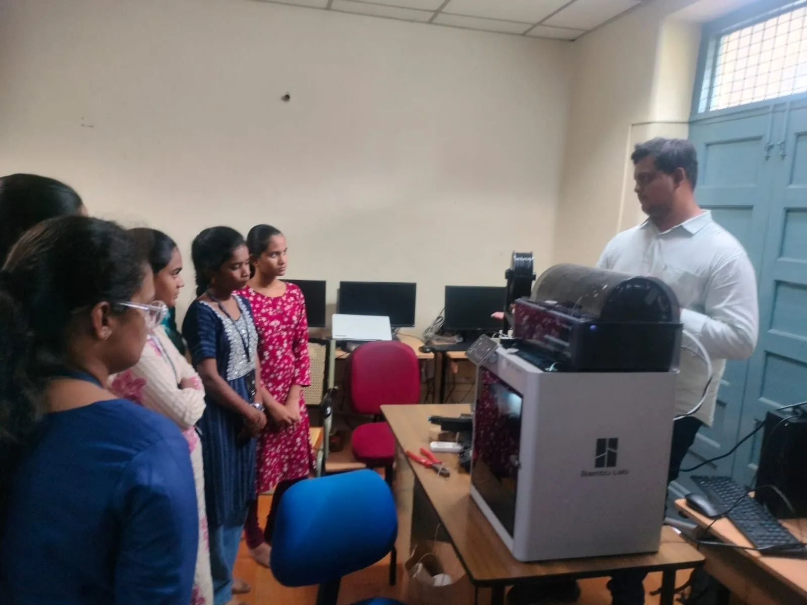 An instructor showing a 3D printer to a group of participants