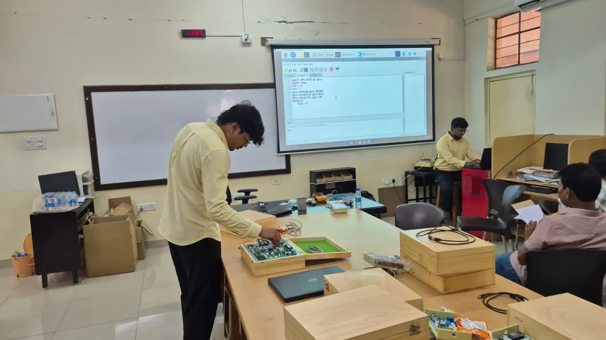 A trainer demonstrating a development board to faculty participants in a lab